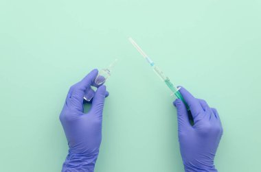 Hemşire elinde eldiven ile tıp doktor mavi masa arka plan üzerinde bir şırınga tutuyor. Üstten görünüm