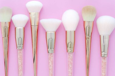 Makyaj fırçaları pembe renkli oluşan arka plan üzerinde kümesi. Üstten bakış noktası, düz yatıyordu.