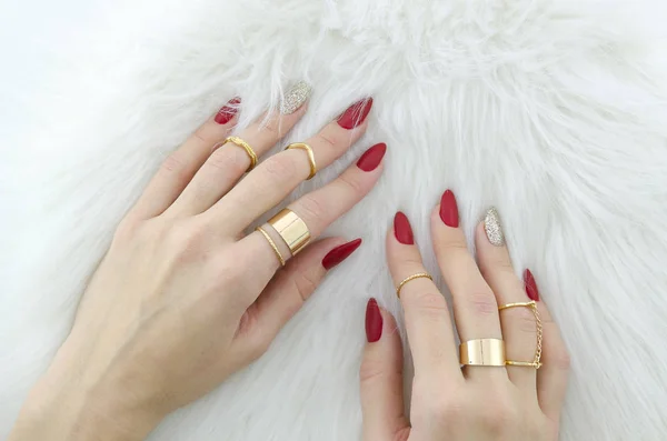 Manos de mujer con uñas rojas arte y joyas sobre fondo de piel . — Foto de Stock