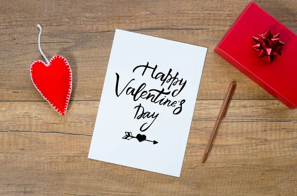Wenskaart met hand belettering wenst happy Valentijnsdag, luxe-geschenketui en handgemaakte vilten speelgoed hart over houten achtergrond — Stockfoto