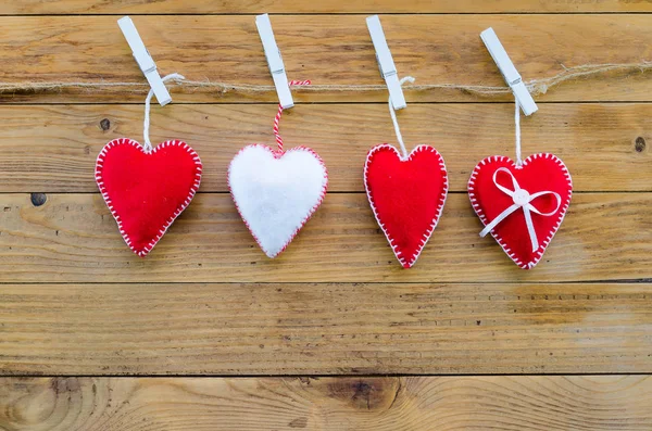 Tres corazones rojos y uno blanco. símbolo de una familia, amor. Sobre fondo de madera — Foto de Stock