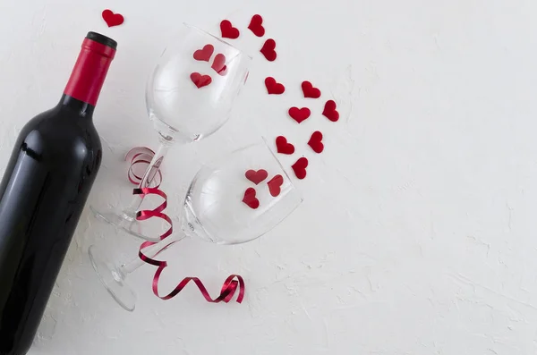 Red wine bottle, with two glasses red hearts and ribbon on white background, top view. Flat lay — Stock Photo, Image