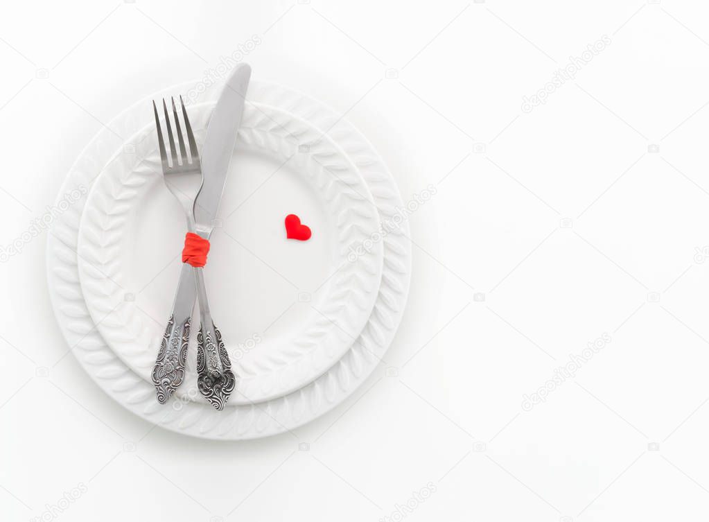 Fork, knife and two red hearts on white plate. Invitation for a romantic dinner, Valentine Day, love, dating concept, copy space,, top view