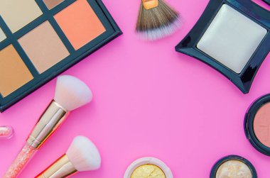 Pembe arka planda set kozmetik. Makyaj tozu, allık, yüz heykelleme için düzeltici için fırçalar yapılan makyajlı çerçeve