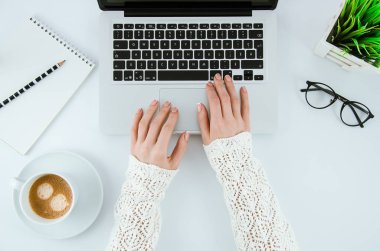 Modern dizüstü bilgisayar üzerinde çalışan ve klavyede yazarak kadın. Kahve, Not defteri ve gözlük fincan beyaz arka plan üzerinde Office Masaüstü. Internet arama kavramı üst görünümü