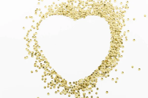 Goud glitters, verspreid in wanorde gevoerde hart vorm geïsoleerd op witte achtergrond met kopieerruimte — Stockfoto