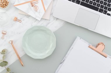 Womens pastel arka plan bloglama. Mermer arka planda bir çay bardağı, pano, bahar lale buket, şapka ve dizüstü bilgisayar ile ofis masası çalışma. Kopya alanı ile üst görünüm