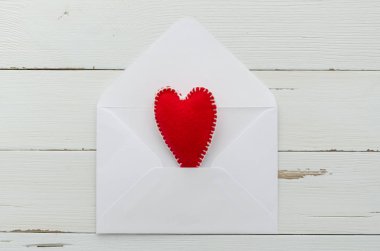 Beyaz rustik ahşap arka planda keçe kırmızı kalp ile üst görünüm romantik posta. Aziz Sevgililer günü konsepti. Düz yatıyordu, kopya alanı