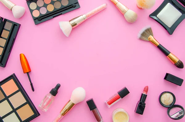 Visão superior de cosméticos em uma mesa rosa. Local de trabalho flat lay com cosméticos, batom e sombra — Fotografia de Stock