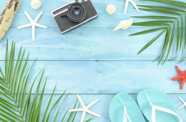 Üst görünüm gezgin aksesuarları, metin için boş alan ile ahşap plakalar arka planda tropikal palmiye yaprağı dalları. Seyahat tatil konsepti. Yıldız balıkları ve plaj terlikleri ile yaz geçmişi