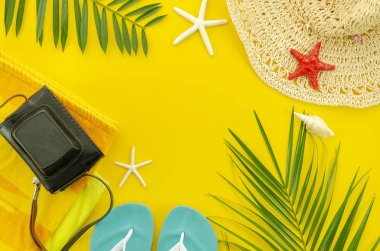 Üst görünüm yaz plaj aksesuarları. Tropikal palmiye yaprağı dalları ve metin alanı ile sarı arka planda hasır şapka ile çerçeve Banner. Yaz düz arka plan yatıyordu