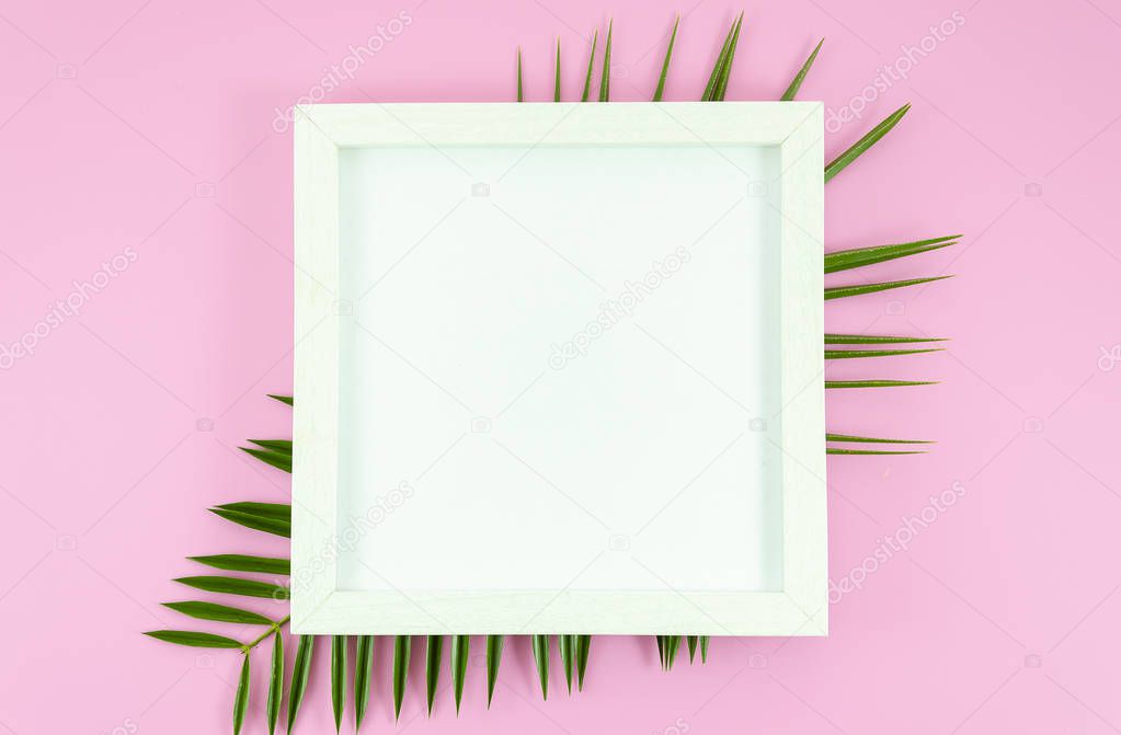 Flat lay white frame with copy space at blank paper list at pink background with tropical leafs from palm tree. Top view mockup