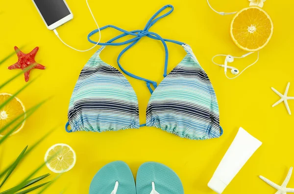 Strandaccessoires mit Bikini, Smartphone, Glas und Hausschuhen. Draufsicht flach legen Sommerreisekonzept. — Stockfoto