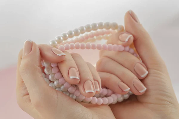 Vrouw hand met een parel ketting. Mooie Franse manicure, natuurlijke nageldesign — Stockfoto