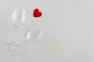Düz iki şarap kadehi ve beyaz izole arka plan üzerinde kırmızı kalp ile romantik bir kavram yatıyordu. Tebrik kartı veya metin başlığı için alan