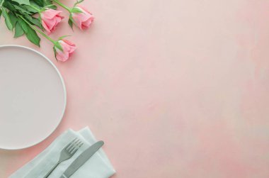 Pembe gül çiçekleri, çanak ve gümüş bıçak, çatal ve peçete ile romantik akşam yemeği için Düz yatıyordu köşe restoran masa. Banner veya menü arka planı için boşluk kopyalama