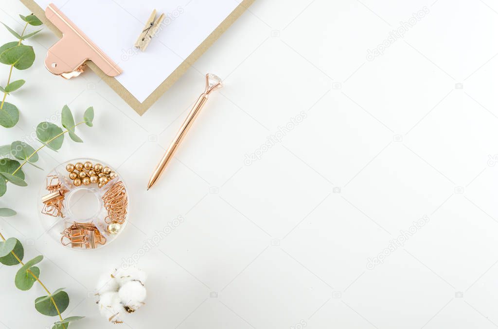 Workplace top view office tools and clipboard with cotton flowers and eucalyptus branches on a white background. Flat lay, copy space