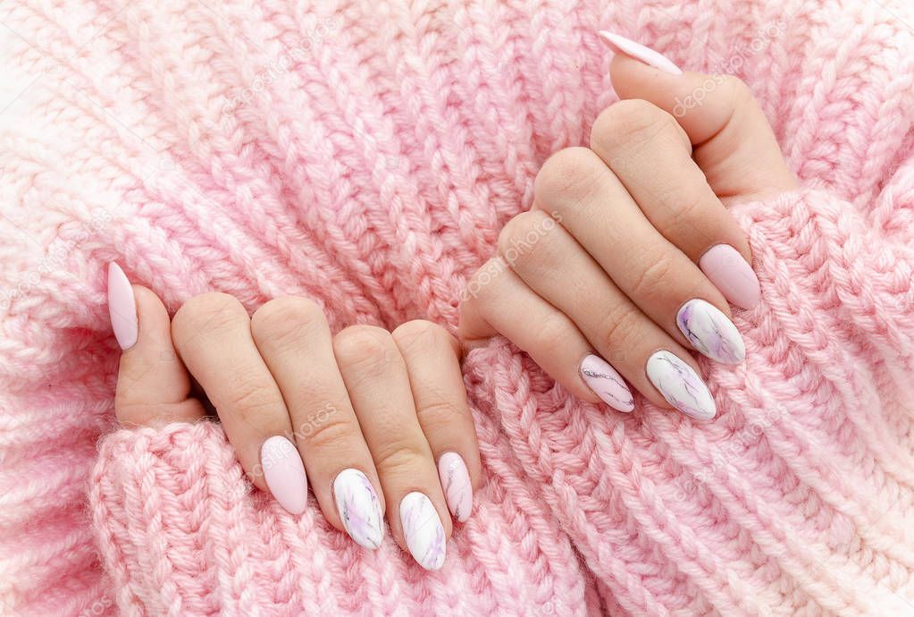 Female hands manicure close up view on pink knitted sweater background. Nail painting effects. Manicure salon banner concept
