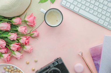 Düzensizliği olan kadınların masaüstü. Laptop, güller ve kahve kupası olan dağınık çalışma alanı. Üst görünüm