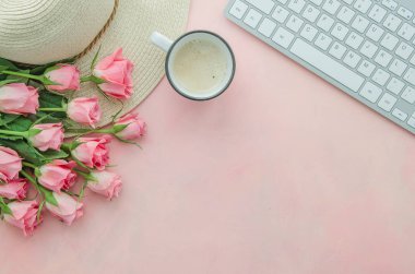 Pembe bir masa, kahve bardağı ve hasır şapka üzerinde pembe gül bir buket ile üst görünüm kadın işyeri. Metin afişi için alan kopyalama
