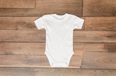 Ahşap arka plan üzerinde üst görünüm beyaz bebek bodysuit. Metin yazısı için boşluk kopyalama