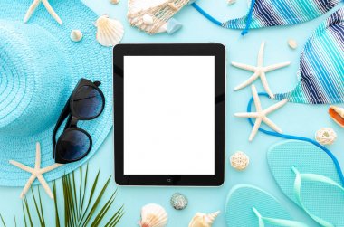Üst görünüm yaz okyanus tatil konsepti mockup. Kadın plaj aksesuarları ile mavi bir arka plan üzerinde Tablet pc