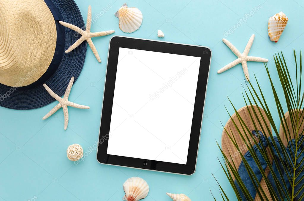 Tablet pc with blank screen mockup. Summer beach concept. Starfishes with palm leaf and beach slippers