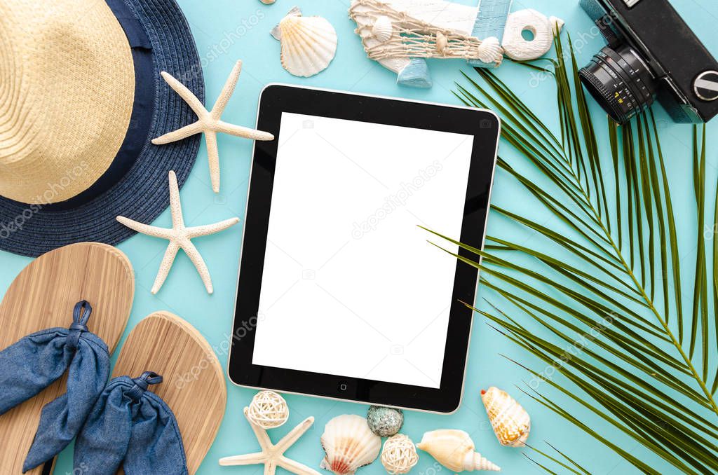 Top view mockup summer sea vacation concept. Tablet pc with a blank screen with womens sunglasses and beach accessories on a blue background