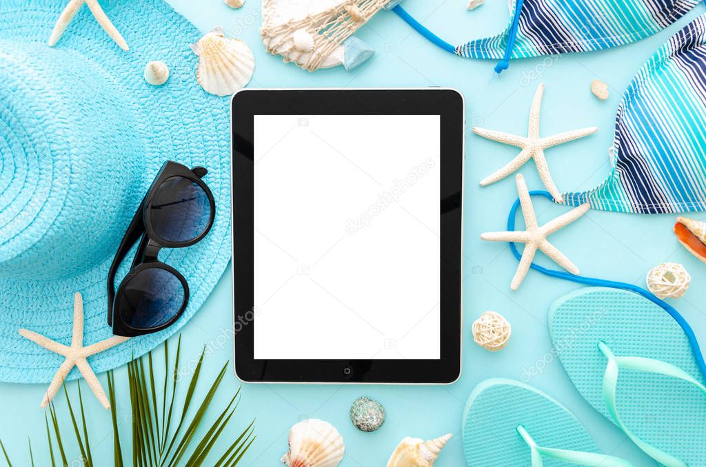Top view summer ocean vacation concept mockup. Tablet pc on a blue background with womens beach accessories