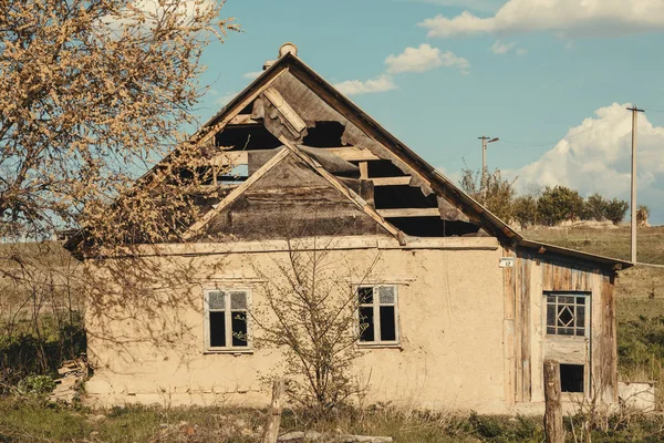 Abandoned old traditional house with a tree at the front in a Ukranian village. Slanted walls, rural devastation. Horizontal shot — Stock Photo, Image