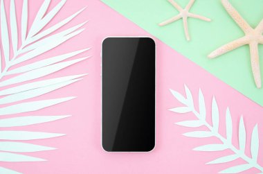 Kağıt palmiye yaprakları ve denizyıldızları ile pop pastel arka plan üzerinde boş ekran ile Çerçeve mockup akıllı telefon. Kopyalama alanı