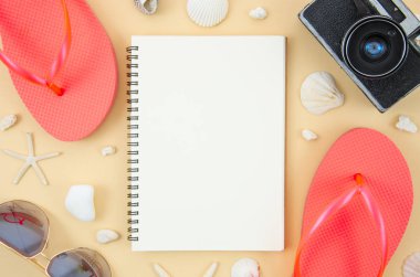 Bir pastel bej arka plan üzerinde plaj aksesuarları terlik ve plaj ile Spiral not defteri mockup. Kopyalama alanı ile üstte görünüm