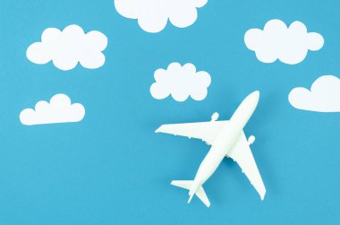 Beyaz kağıt mavi pastel arka plan üzerinde bulutlar kesilmiş düz yatıyordu model düzlem. Seyahat el ilanı için en iyi görünüm arka plan