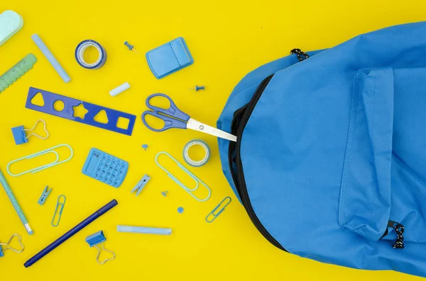 Prodotti di cancelleria blu vista dall'alto con una borsa della scuola su uno sfondo giallo. Flat lay back al concetto di scuola — Foto Stock