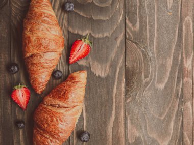 Düz Fransız kahvaltı yatıyordu. Ahşap plakalar üzerinde çilek ile üst görünüm mockup taze kruvasanlar, kopya alanı ile üst görünüm