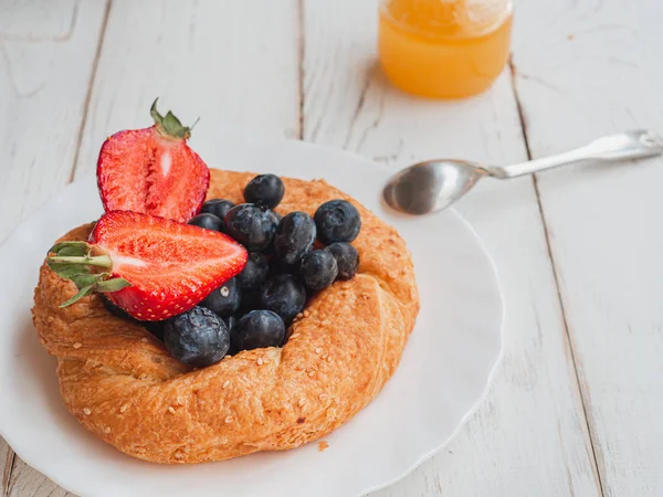 Panecillo fresco con arándanos y fresas sobre un fondo blanco. Desayuno francés de verano — Foto de Stock