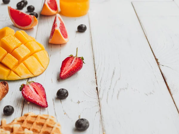 Summer breakfast with waffle and fruit slices. Mango, strawberry, and cherry on wooden background — Stock Photo, Image