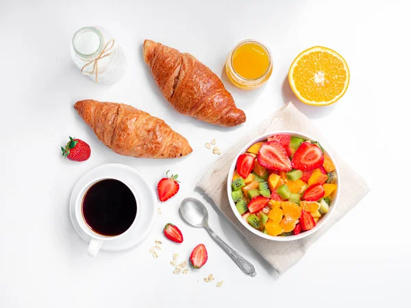 Vista superior del desayuno de verano con tazón de ensalada de frutas frescas saludables, café y cruasanes. Piso sobre fondo blanco — Foto de Stock