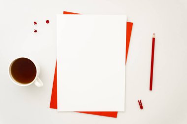 İş yeri malzemeleri, bir fincan çay ve boş A4 kağıt listesi. Kırmızı ve beyaz renkler. Üst görünüm, kopyalama alanı olan düz uzanma