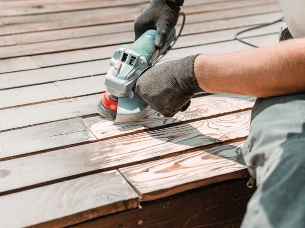 Male hands polishing dark wooden plank with angle grinder and metal brush — Stock Photo, Image