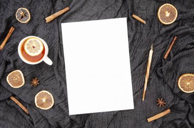 Boş A4 kağıt listesi ile Sonbahar yazarlar işyeri kavramı mockup. Nib kalem, siyah kumaş arka plan üzerinde limon dilimi ve tarçın ile çay. Üst görünüm, kopyalama alanı ile düz yatıyordu