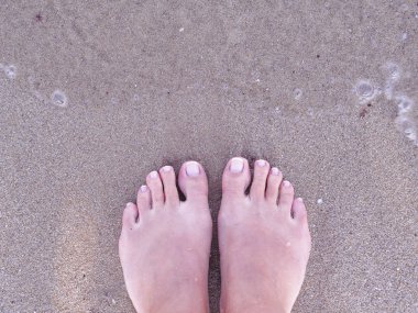 Kum üzerinde Fransız çivi ile üst görünüm kadın ayaklar. Plaj düz yatıyordu