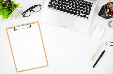 Dizüstü bilgisayar ve boş pano ile üst görünüm beyaz masa. Metin için kopyalama alanı ile mockup