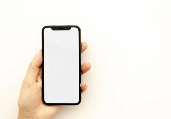 Dames hand houden de zwarte smartphone met grote blanco scherm geïsoleerd op wit. Top View mockup horizontale banner — Stockfoto