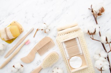 Üst görünüm sıfır atık banyo aksesuarları, doğal sisal fırça, ahşap tarak, katı sabun ve şampuan barlar, yeniden kullanılabilir pamuk mermer arka plan üzerinde kaldırma pedleri makyaj. Pamuk ve ahşap konsepti