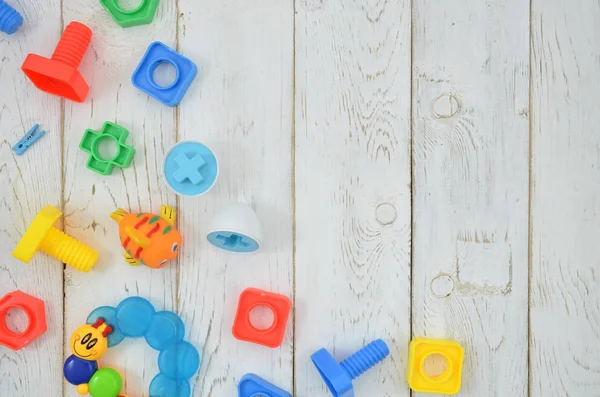 Красочные игрушки сверху и рама строительного комплекта на белом деревянном фоне. Макет с пространством для копирования вашего текста — стоковое фото