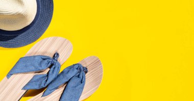 Sarı arka plan üzerinde düz yatıyordu tavel kavramı. Hasır şapka ve plaj terliği. Basılı alanla sabit ışık ve gölgeler mockup