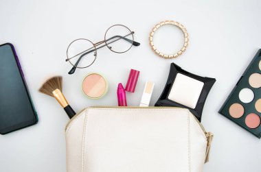 Üst görünüm kozmetik ve fırçalar, gözlük ve akıllı telefon beyaz izole ile çanta makyaj. Güzellik konsepti