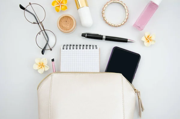 Flat lay beauty blogger concept. Make up bag with cosmetics and brushes, glasses and smartphone isolated on white