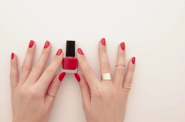 Piso laico arreglado manos de las mujeres con esmalte de uñas rojo botella aislada en blanco. Barnizado de uñas en color rojo. Concepto de manicura — Foto de Stock